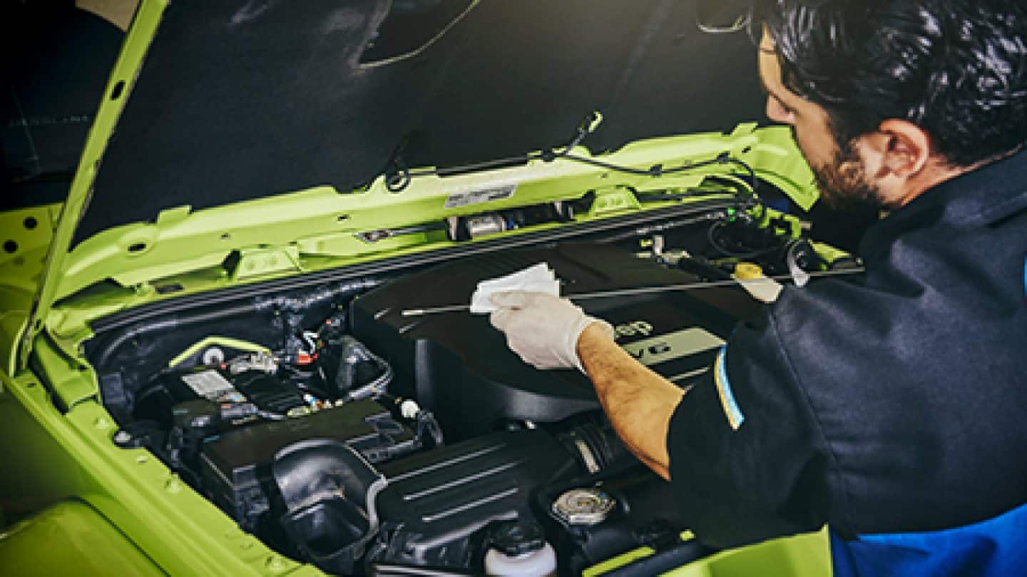 Man checking the oil of a neon green V6 jeep wrangler