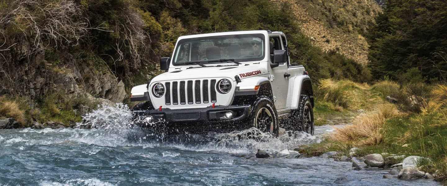 The 2021 Jeep Wrangler Rubicon being driven across a stream.