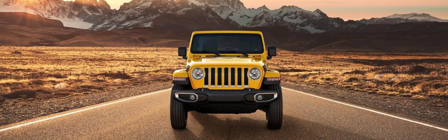 A head-on view of the 2021 Jeep Wrangler Sahara against a mountain backdrop.