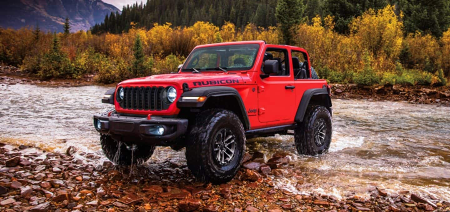 Trail Rated 4x4. Two 2022 Jeep Wrangler Rubicon 4x4s parked on separate rock outcroppings overlooking a lake in the distance.