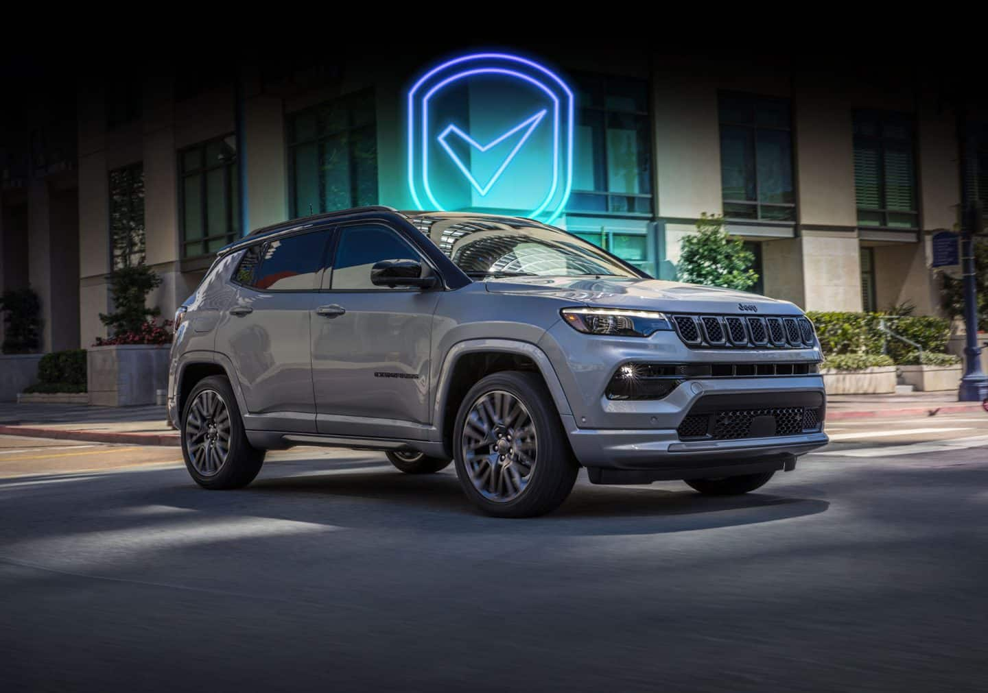 Un Jeep Compass High Altitude 2023 andando por una intersección de calles de una ciudad. Gran marca de verificación de neón superpuesta sobre el fondo.