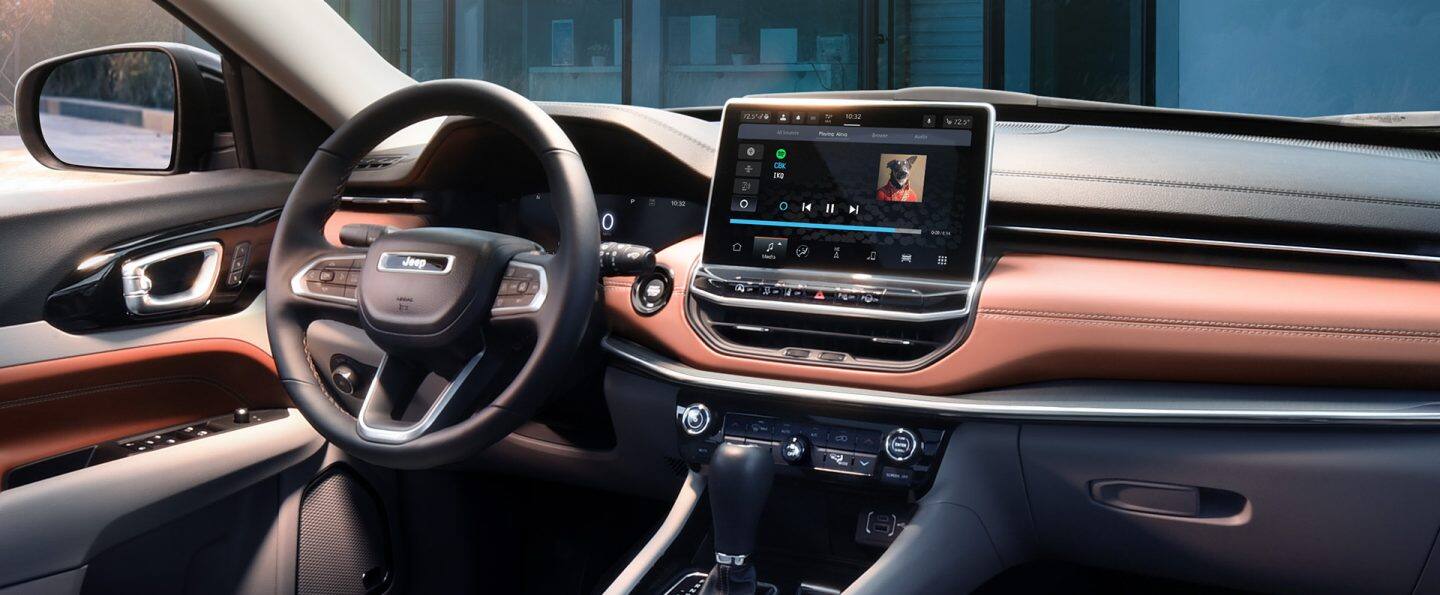 The interior of the 2023 Jeep Compass Limited focusing on the steering wheel and Uconnect touchscreen.