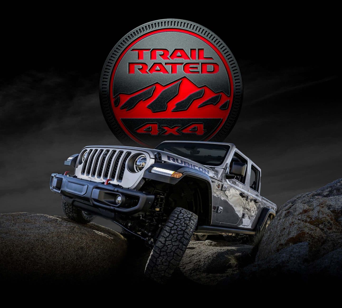 Trail Rated 4x4. The 2023 Jeep Gladiator Rubicon being driven on rocky terrain with one wheel elevated as it climbs a boulder.