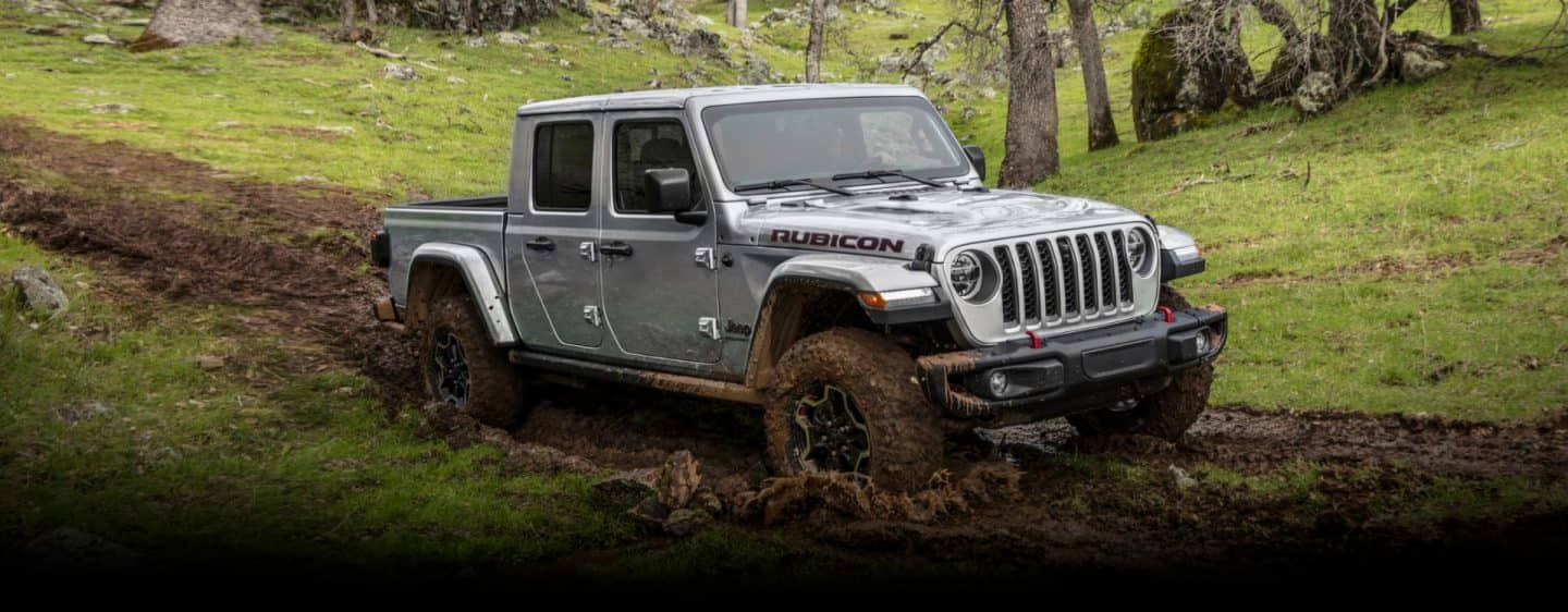 La Jeep Gladiator Rubicon 2023 andando por un sendero de tierra, con las ruedas y la parte inferior de la carrocería salpicadas con barro.