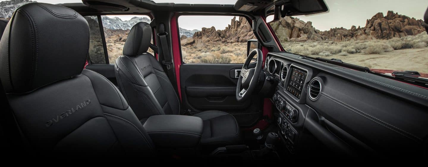 El interior de la Jeep Gladiator Overland 2023 sin el techo, con un primer plano de los asientos delanteros y el tablero.
