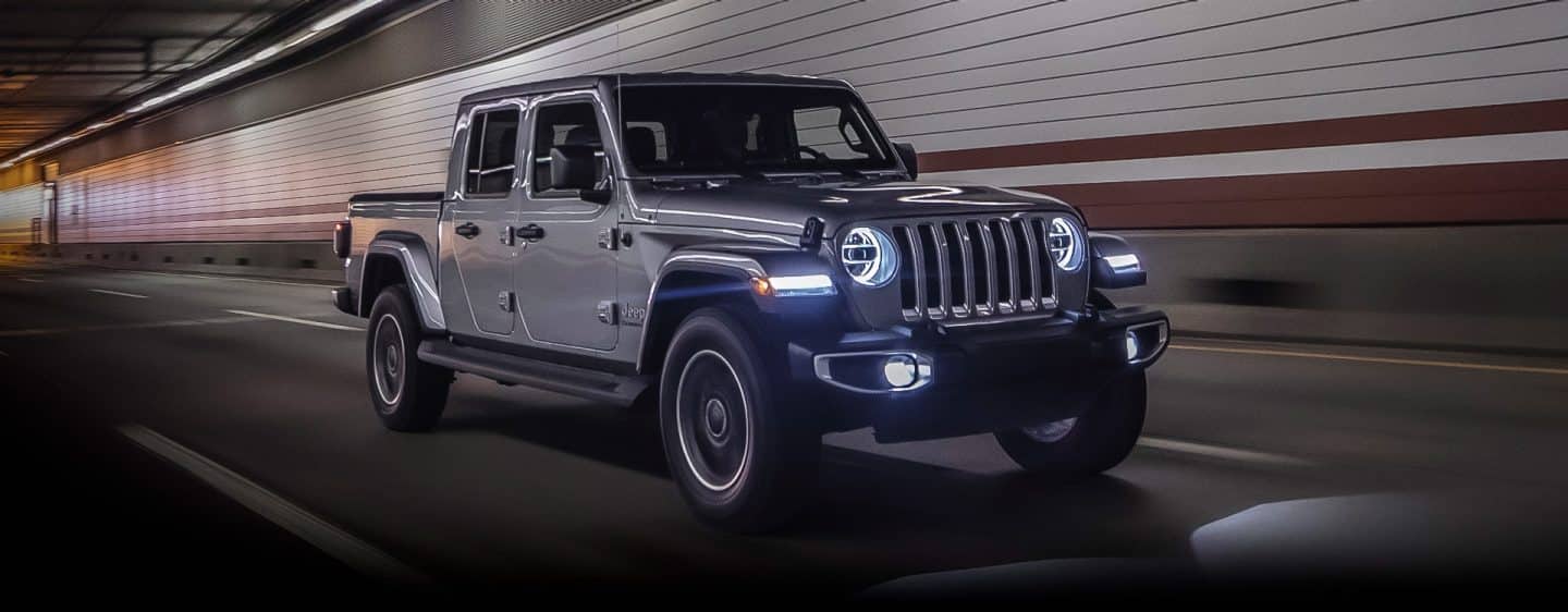 The 2023 Jeep Gladiator Overland with its headlamps and fog lamps lit, being driven through a tunnel.