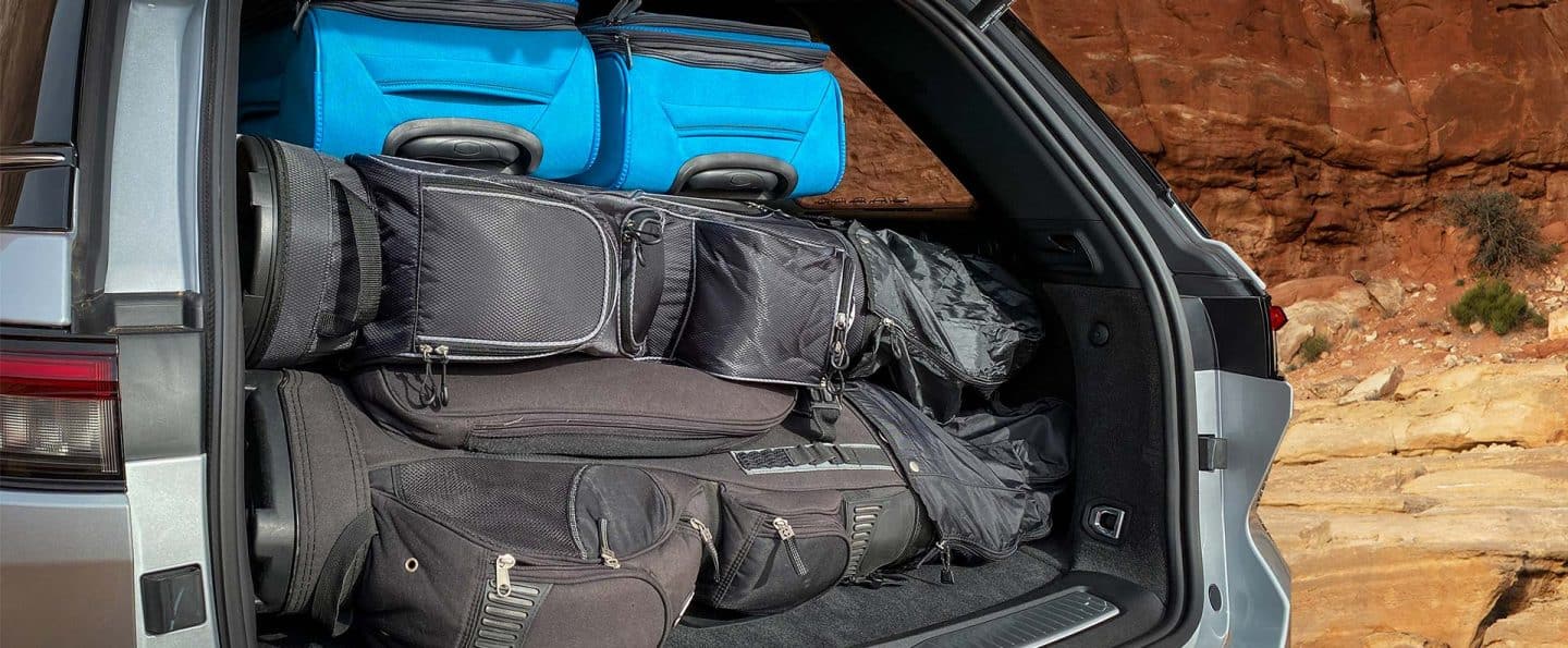 El área de carga trasera del Jeep Grand Cherokee 2023 con dos bolsas de golf y dos maletas de equipaje.