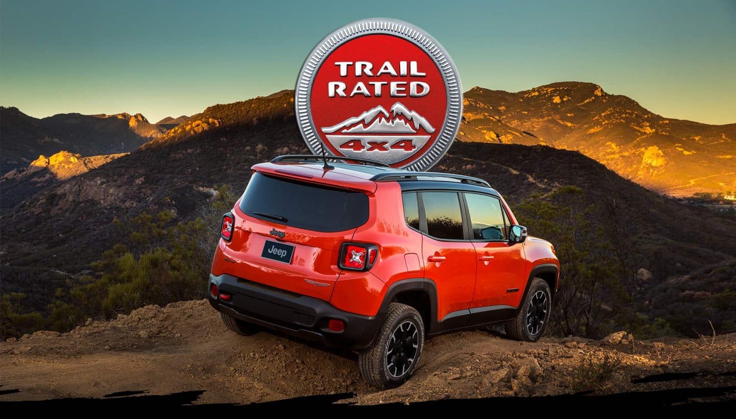 Trail Rated 4x4. Vista trasera de un Jeep Renegade Trailhawk 2023 rojo circulando por un camino de tierra en las montañas.