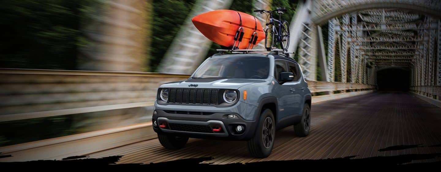 Un Jeep Renegade Trailhawk 2023 cruzando un puente con un kayak y una bicicleta de montaña amarrados en la parrilla portaequipaje.