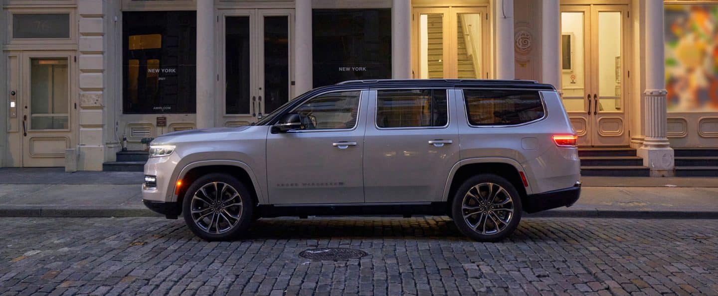 A side profile of the 2023 Grand Wagoneer Series III as it is stopped at the curb on a cobble-stoned street.