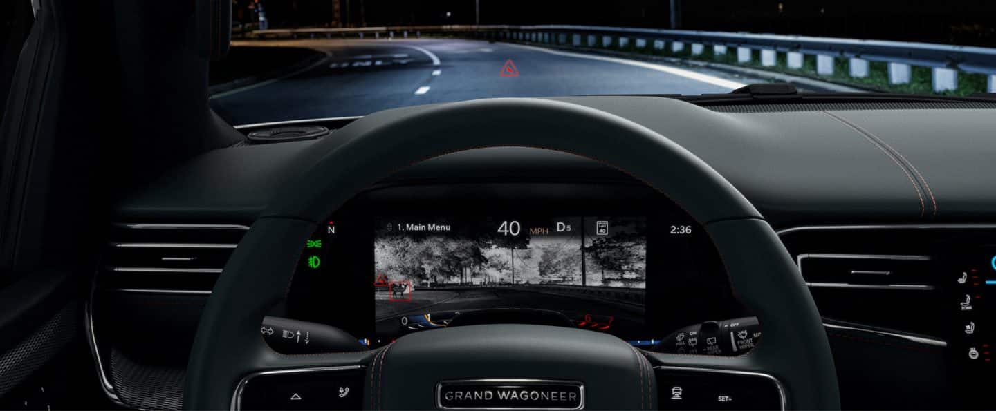 La pantalla de información para el conductor en el panel de instrumentos en el Gran Wagoneer Series III 2023, que muestra una vista nocturna de la carretera con posibles obstáculos resaltados en rojo.