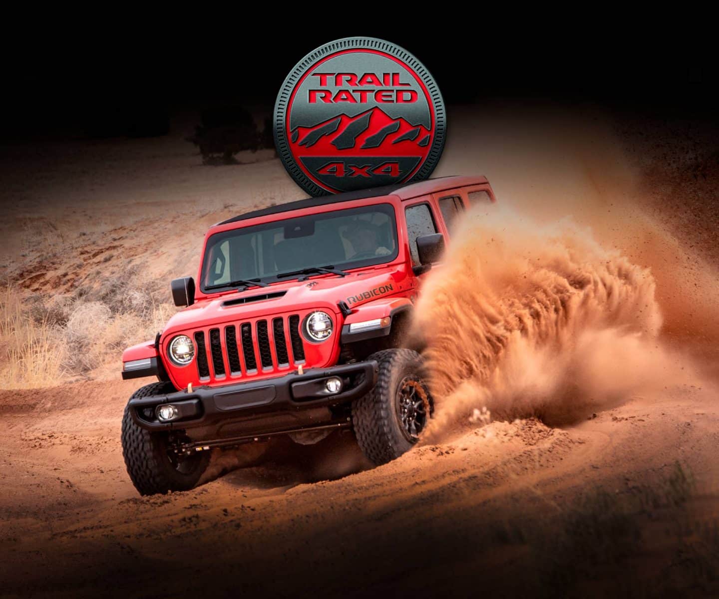 The 2023 Jeep Wrangler Rubicon 392 descending a dune in the desert as sand is kicked up to the top of the side windows. The Trail Rated 4x4 badge.