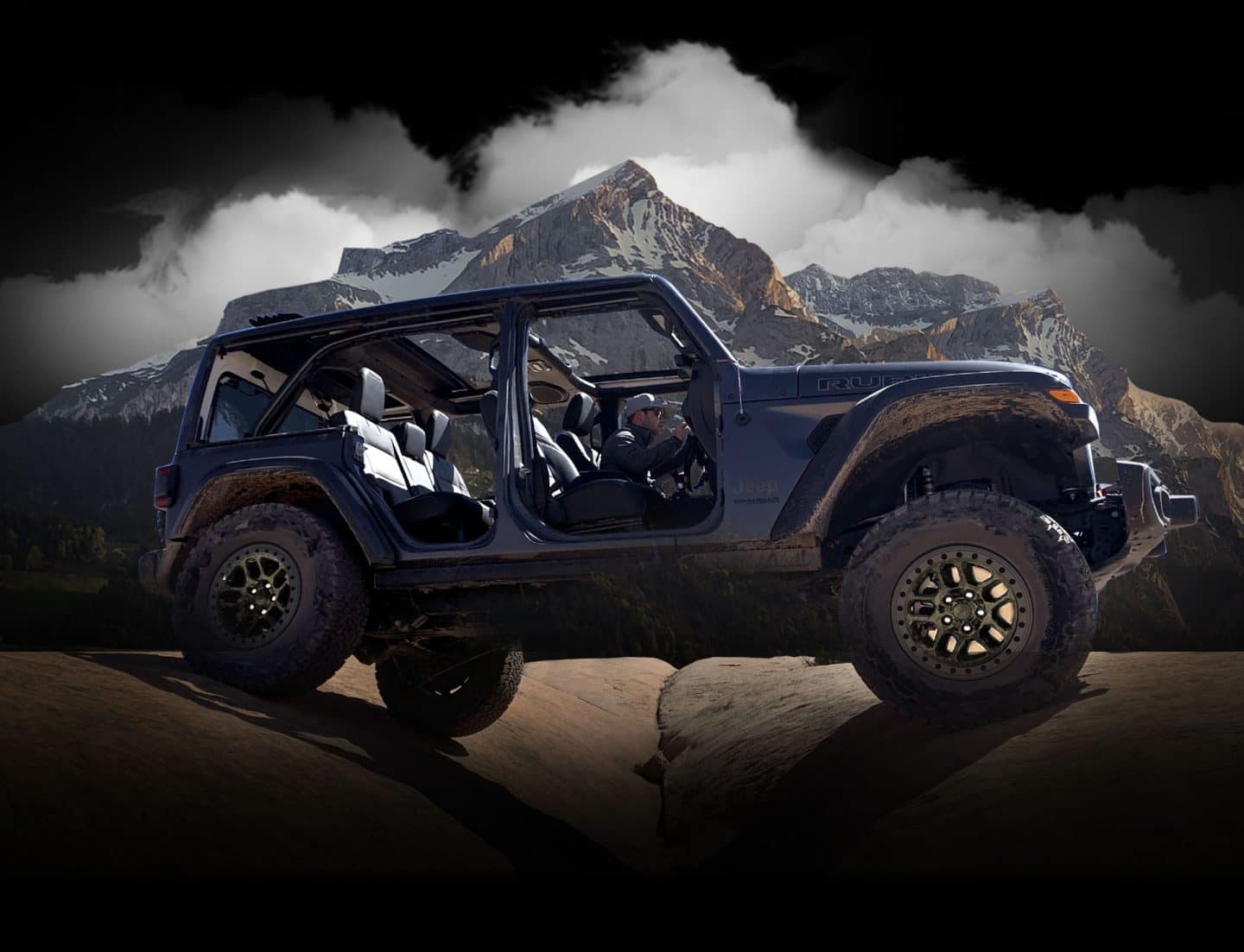 The 2023 Jeep Wrangler Rubicon 392 with Xtreme Recon Package straddling two boulders as it's driven off-road with its doors off and top open.