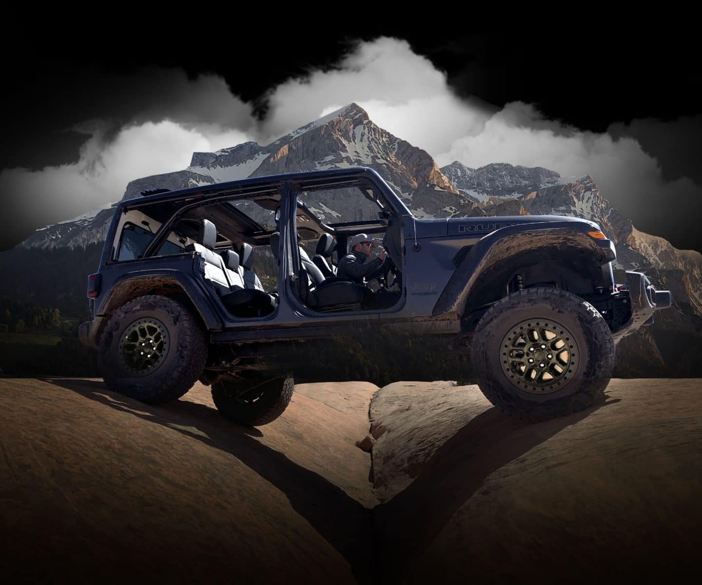 The 2023 Jeep Wrangler Rubicon 392 straddling two boulders as it's driven off-road with its doors off and top open.