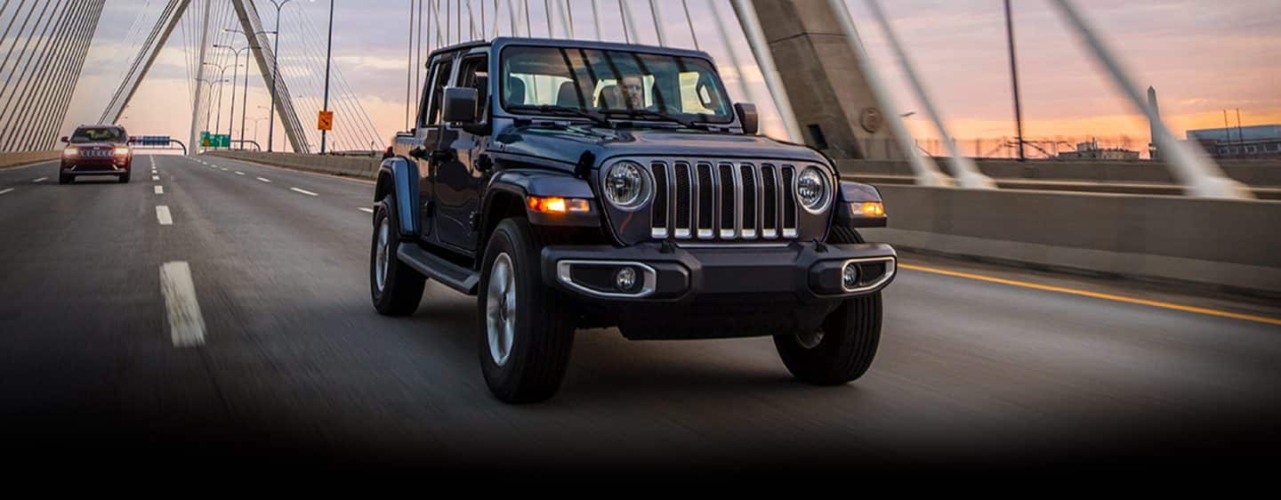 The 2023 Jeep Wrangler Overland being driven over a bridge.