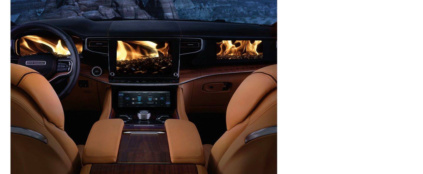 Clusterul digital pentru informații despre șoferi, ecranul tactil Uconnect și afișajul interactiv pentru pasageri din Grand Wagoneer 2024, toate afișând un videoclip cu un foc de tabără în flăcări.