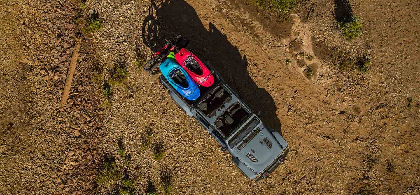 Un ángulo descendente de un Jeep Gladiator Mojave X gris 2025 con sus puertas y techo retirados, conducidos en arena suelta, creando pistas pesadas a medida que avanza.