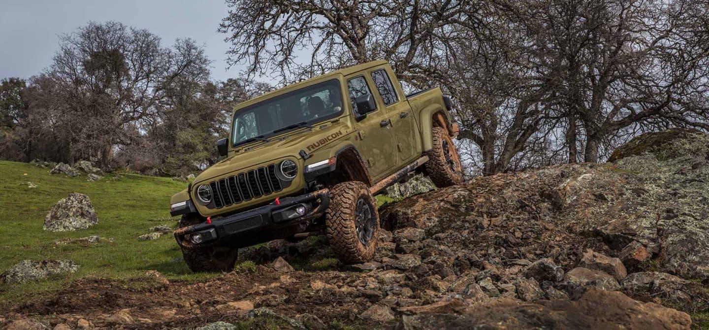 Un Jeep Gladiator Rubicon X verde oliva de 2025 que desciende por un sendero escarpado y rocoso fuera de carretera.