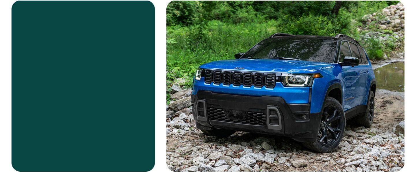 Un Jeep Cherokee Overland 2026 rojo circulando por una playa, levantando arena mientras avanza.