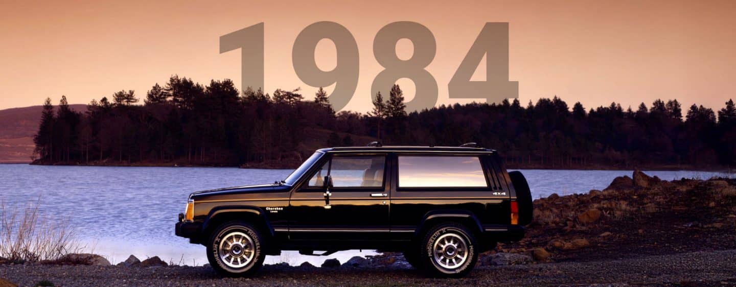 Perfil del lado del conductor de un Jeep Cherokee Laredo negro clásico estacionado al lado de un lago. 1984.