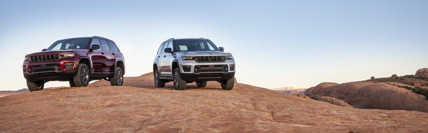 A 2022 Jeep Grand Cherokee Trailhawk and Trailhawk 4xe parked on a rocky plateau.