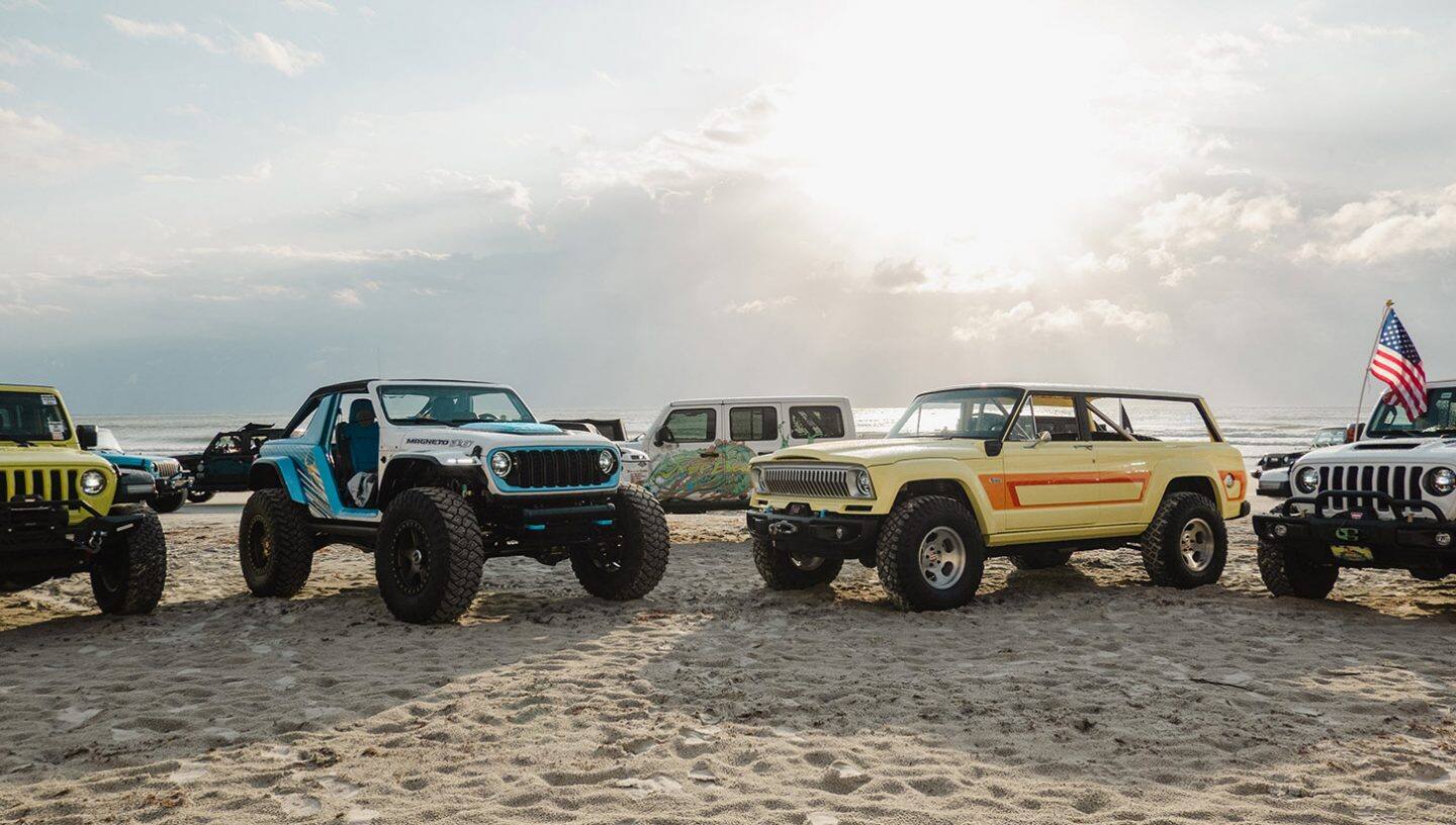 Plusieurs véhicules Jeep Brand Concept garés sur une plage avec le Jeep Wrangler Magneto 3.0 Concept et le Jeep Cherokee 4xe Concept de 1978 au premier plan.
