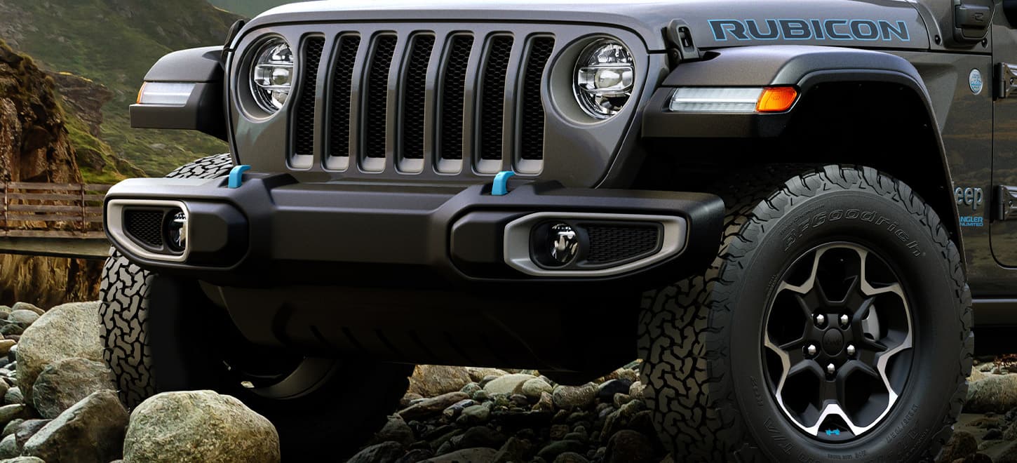 A close-up of the front grille of the 2023 Jeep Wrangler Rubicon 4xe being driven over large rocks.