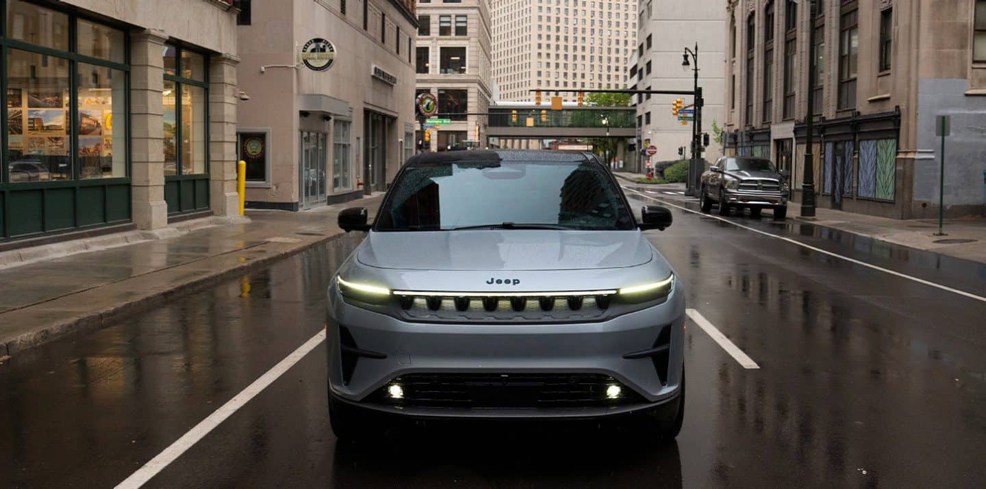 Un Jeep Wagoneer S Launch Edition 2025 plateado circulando por una calle de ciudad bajo la lluvia.