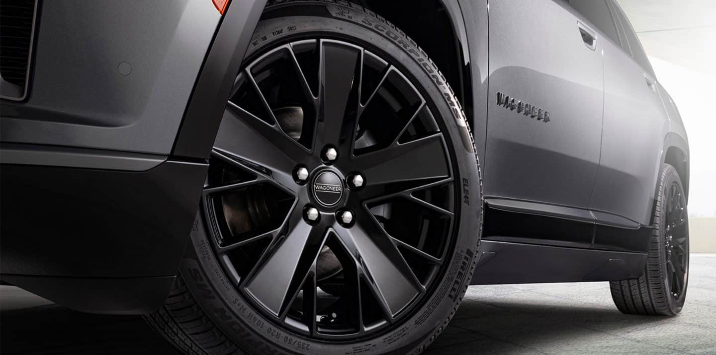Un Jeep Wagoneer S Launch Edition 2025 plateado circulando por una calle de ciudad bajo la lluvia.