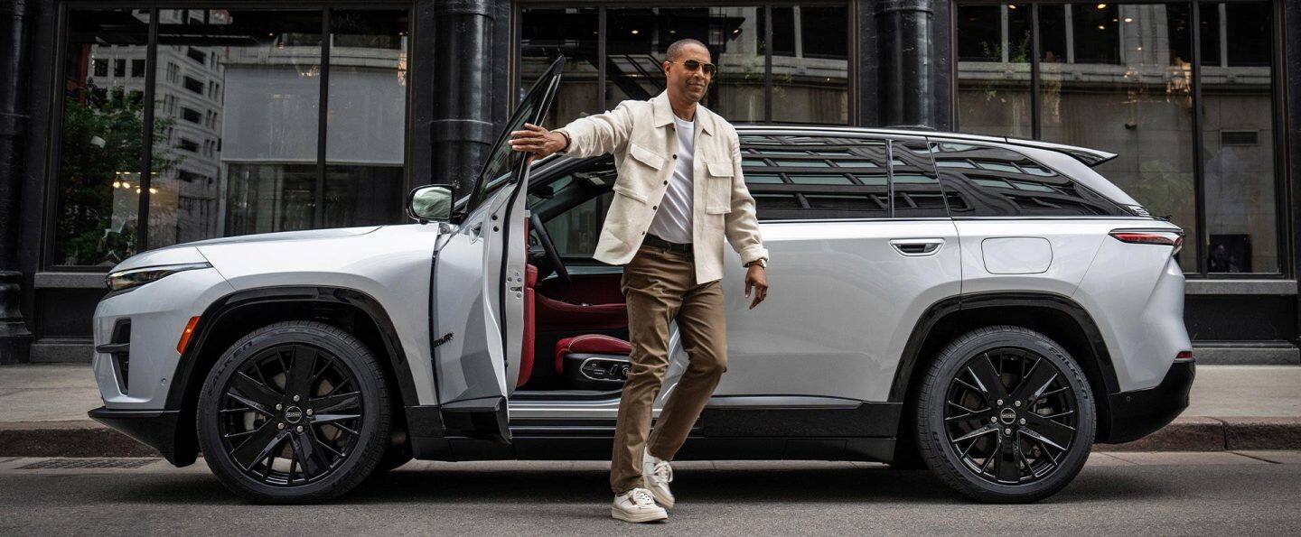 Un hombre sale de la puerta del conductor de un Jeep Wagoneer S Launch Edition 2025 blanco.