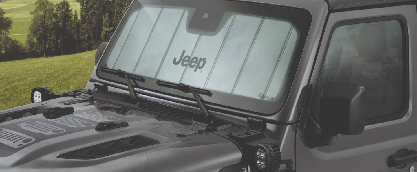 Perfil del lado del pasajero de un Jeep Wrangler Rubicon X 4xe 2025 rojo trepando una colina de peñascos cubiertos de arena.