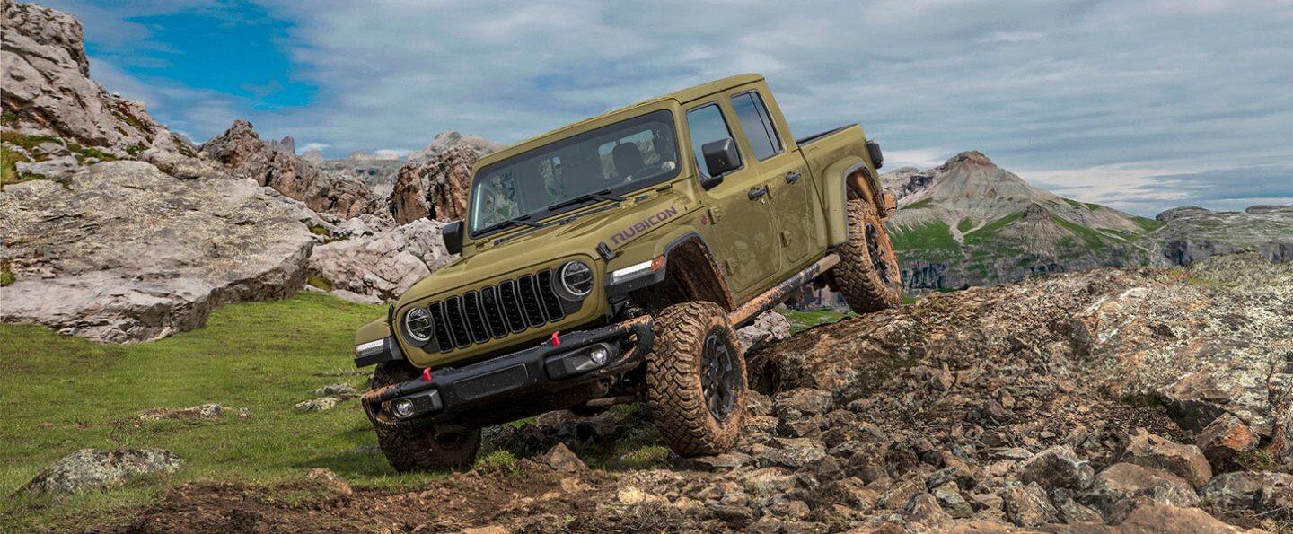 Una Jeep Gladiator Rubicon X 2026 verde oliva descendiendo por un sendero todoterreno rocoso e irregular.