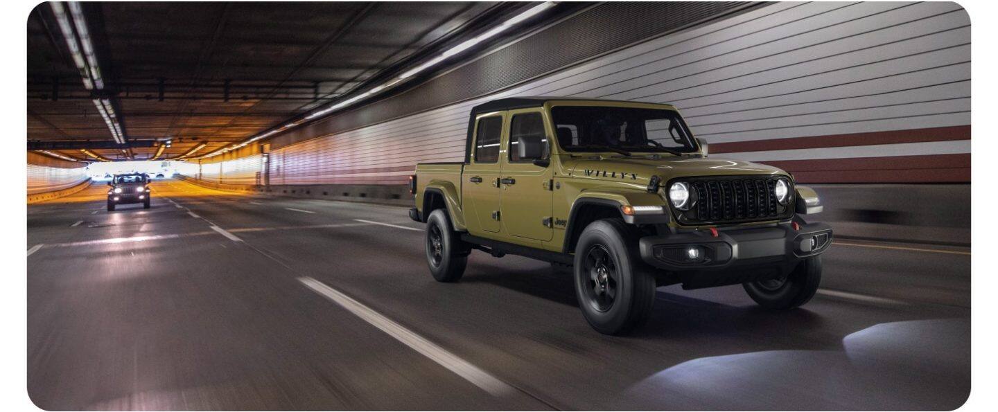 Una Jeep Gladiator Rubicon X 2026 azul circulando por una carretera cubierta de nieve, a través de las montañas.