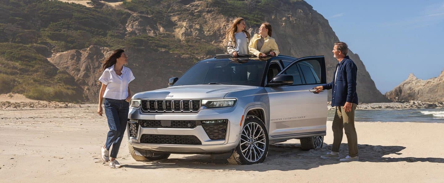 Un perfil del lado del pasajero de un Jeep Grand Cherokee L Summit 2026 negro estacionado en la sinuosa entrada para vehículos de una casa grande.