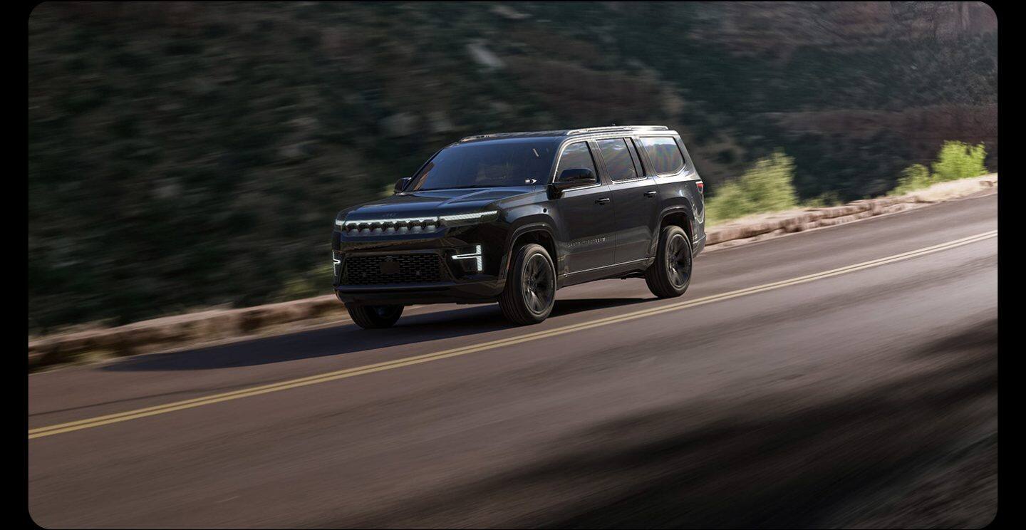 Una Jeep Grand Wagoneer Summit Reserve Obsidian 2026 negra circulando por una autopista, con el fondo desenfocado para mostrar movimiento.