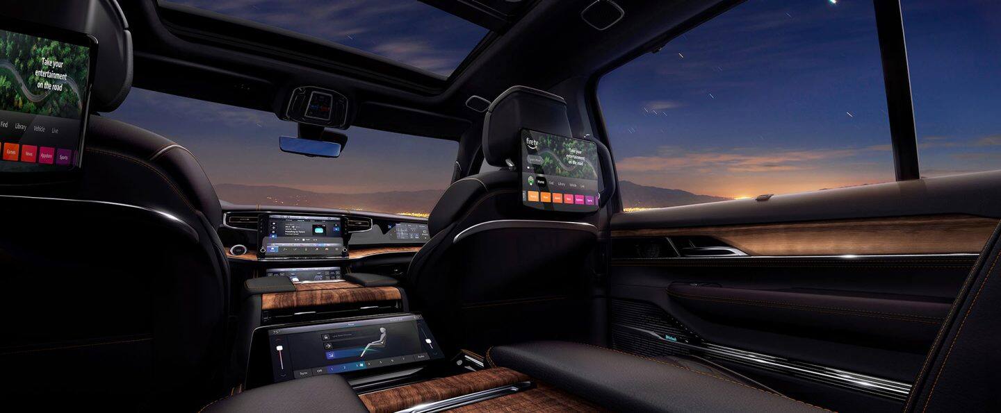 La segunda fila de un Jeep Grand Wagoneer 2026 con las dos pantallas táctiles de entretenimiento traseras montadas en el respaldo de los asientos delanteros.