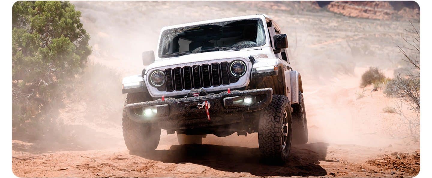 Un Jeep Wrangler Rubicon 2026 blanco de cuatro puertas, circulando por una carretera en la ciudad.