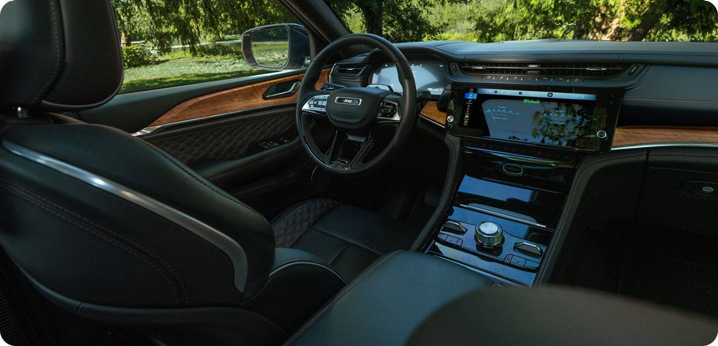 El interior de la Jeep Grand Cherokee Summit 2027, con el foco puesto en el guía, la pantalla táctil Uconnect y la consola central.