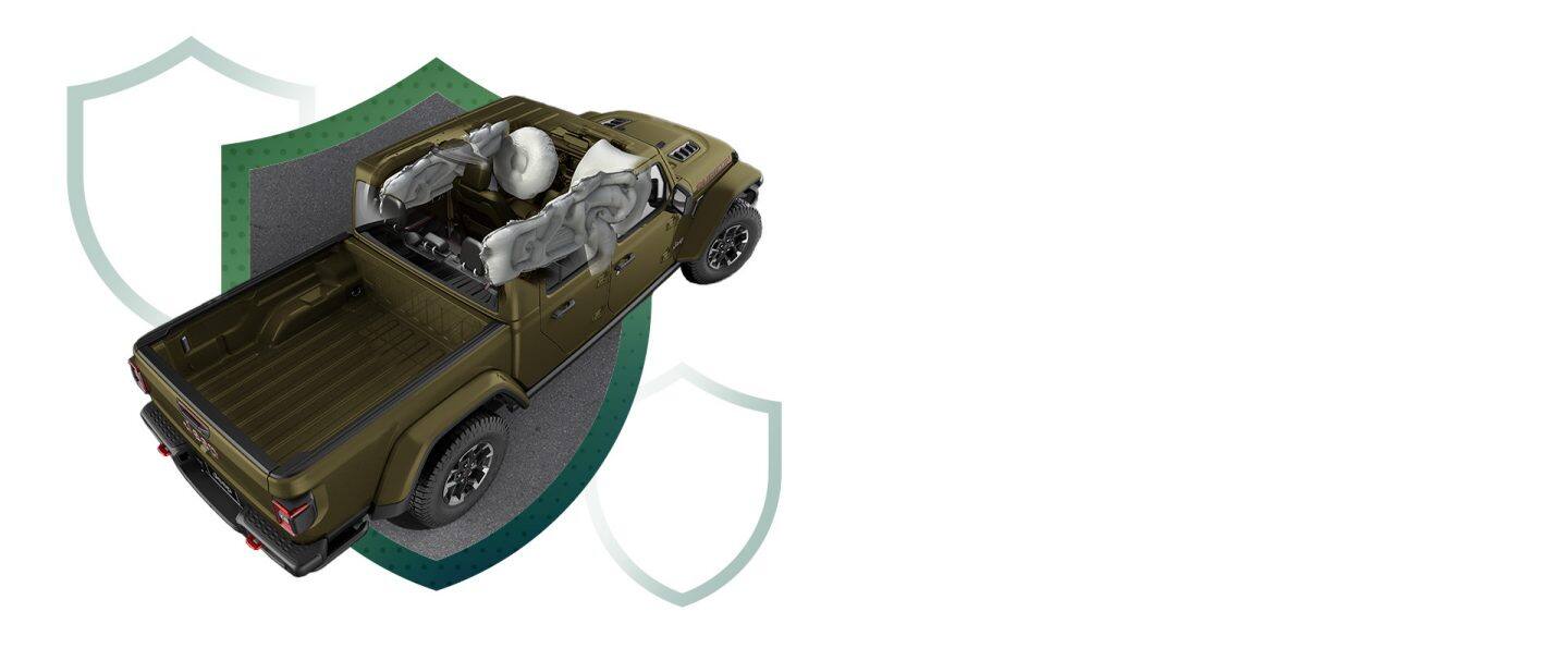 Un Jeep Gladiator Rubicon X 2026 en color gris oliva con las bolsas de aire infladas, para demostrar cómo se protege a los ocupantes del lado de la ventana.