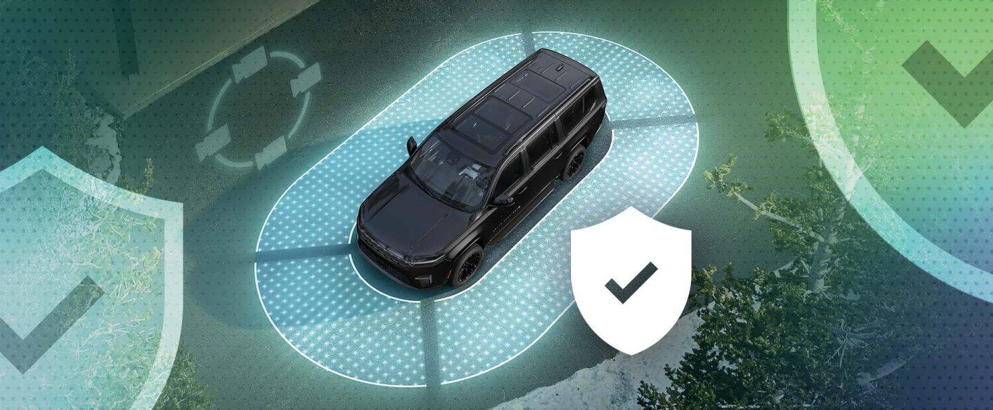 Ángulo superior de una Jeep Grand Wagoneer 2026, rodeado por un óvalo iluminado, con un escudo que contiene una marca de verificación junto a la SUV.