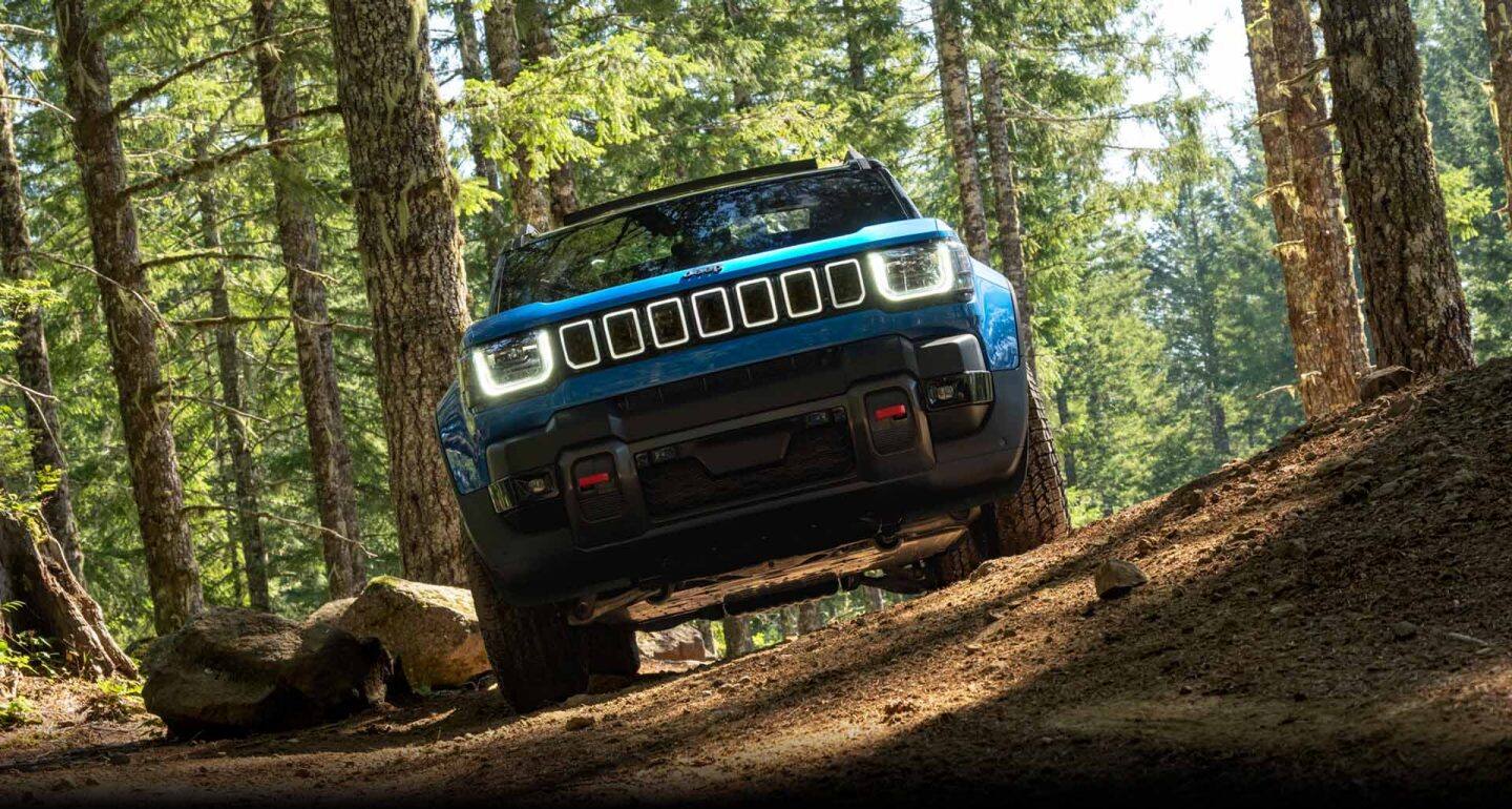 Una Jeep Recon Moab 2026 azul, estacionada en un sendero en el bosque.