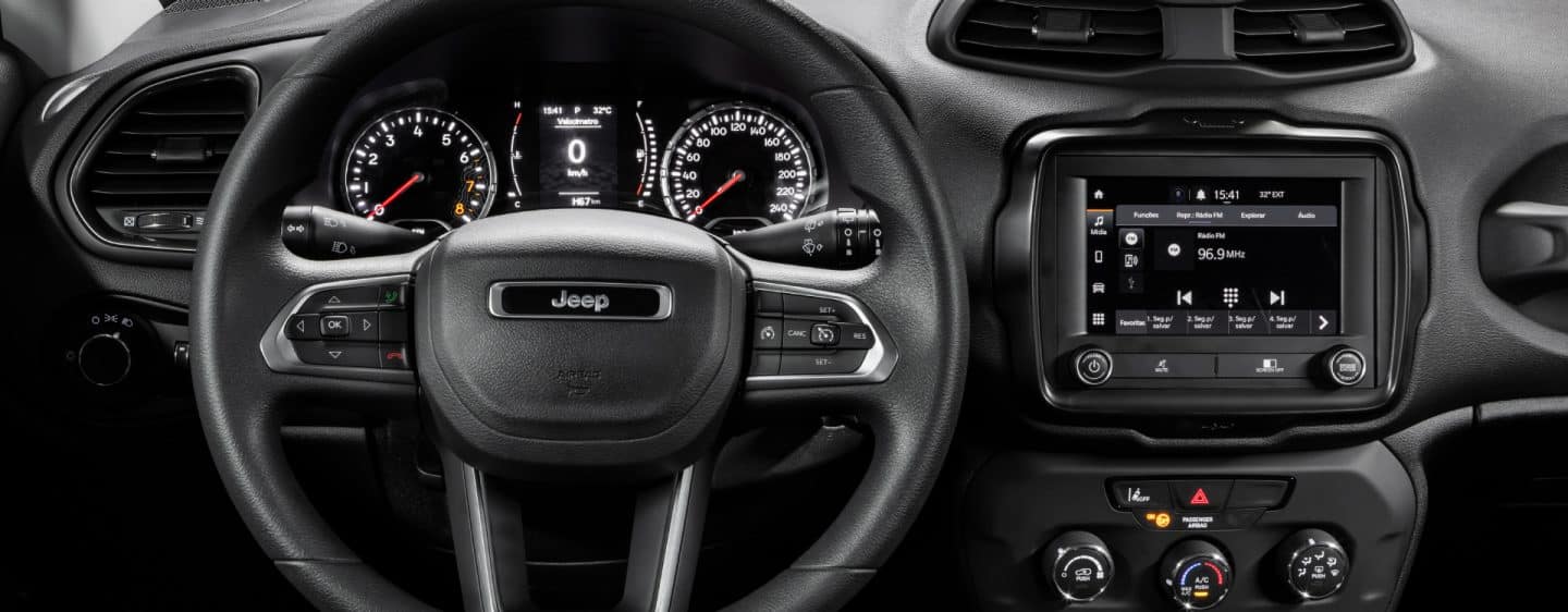 A close-up of the touchscreen in the 2023 Jeep Renegade with the driver's hand reaching for the phone icon on the screen.