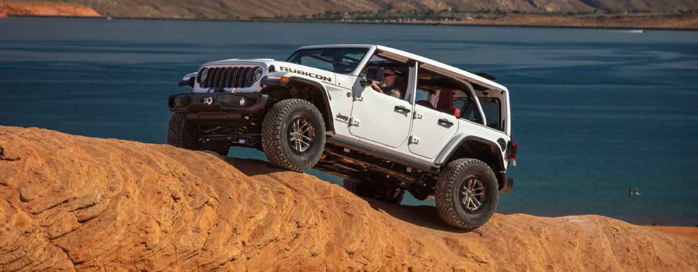 The 2023 Jeep Wrangler Rubicon 392 with its Sky One-Touch Power Top open as it is driven up a rocky slope.