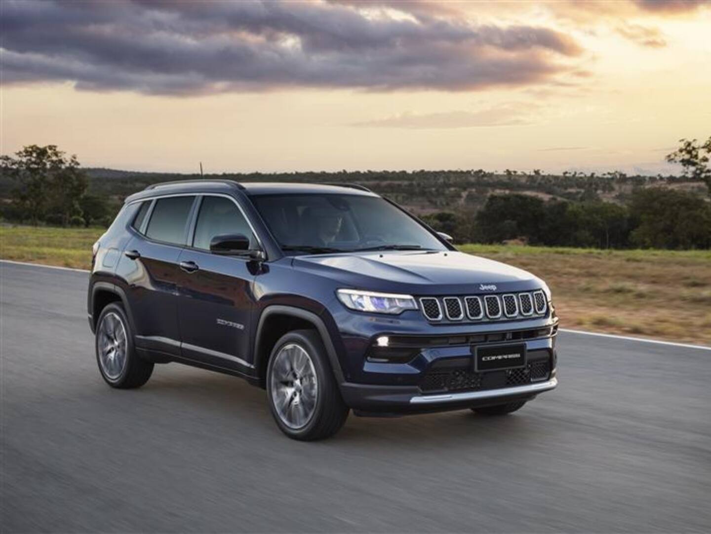 A 2025 Jeep Compass Trailhawk being driven on a hill off-road, with the tires kicking up dust. The Trail Rated 4x4 badge.
