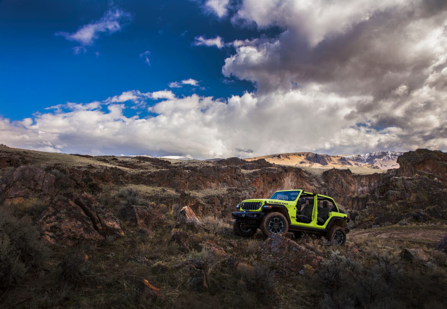 Un Jeep Wrangler Rubicon 392 2025 con el techo eléctrico Sky de un toque abierto circulando por una pendiente rocosa.