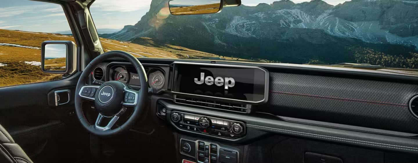 The front row of the 2025 Jeep Wrangler Rubicon with the steering wheel, dashboard and touchscreen included.