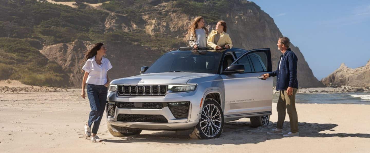 Una Jeep Grand Cherokee Summit 2026 gris circulando por una carretera en la costa.