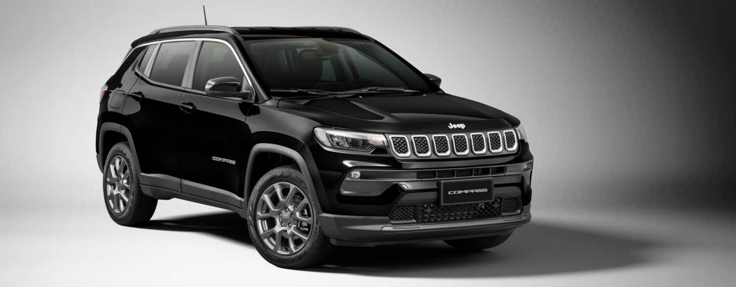 A raised head-on view of a 2023 Jeep Compass Trailhawk being driven off-road through a wooded trail.