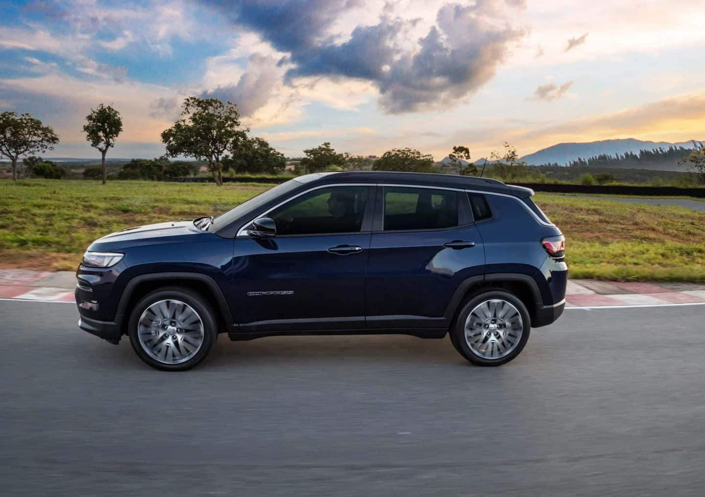 The 2023 Jeep Compass High Altitude parked on a dry, desert-like surface, with mountains in the distant background. 