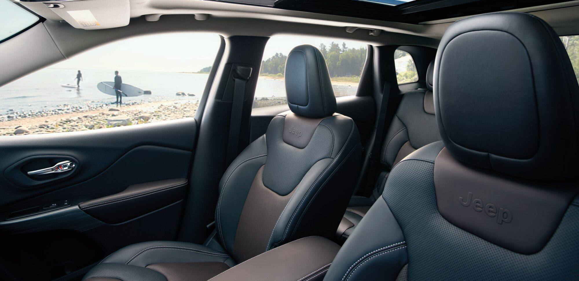 Black 2018 Jeep Cherokee seats with surfers in background through window
